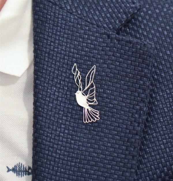 Modern silver dove lapel pin on a blazer
