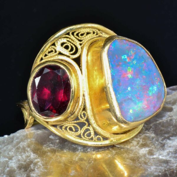 Sustainable gold filigree opal and garnet ring displayed